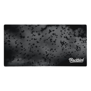 A graphic image of numerous blackbird silhouettes against a cloudy grey background with the word "blackbird" in the lower right corner on a Desk Mat (18x36").